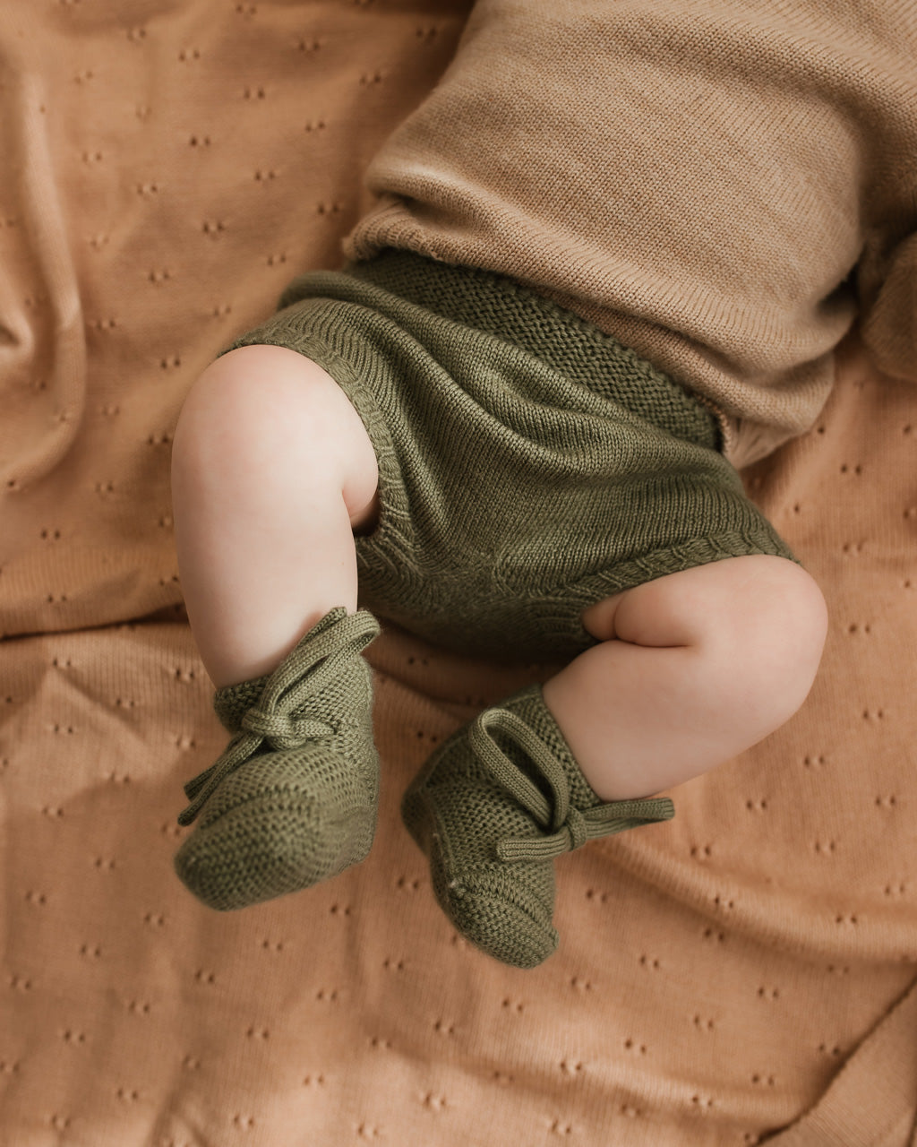 Baby trägt die Hvid Strickschuhe Booties in Artichoke, erhältlich bei Bärechind