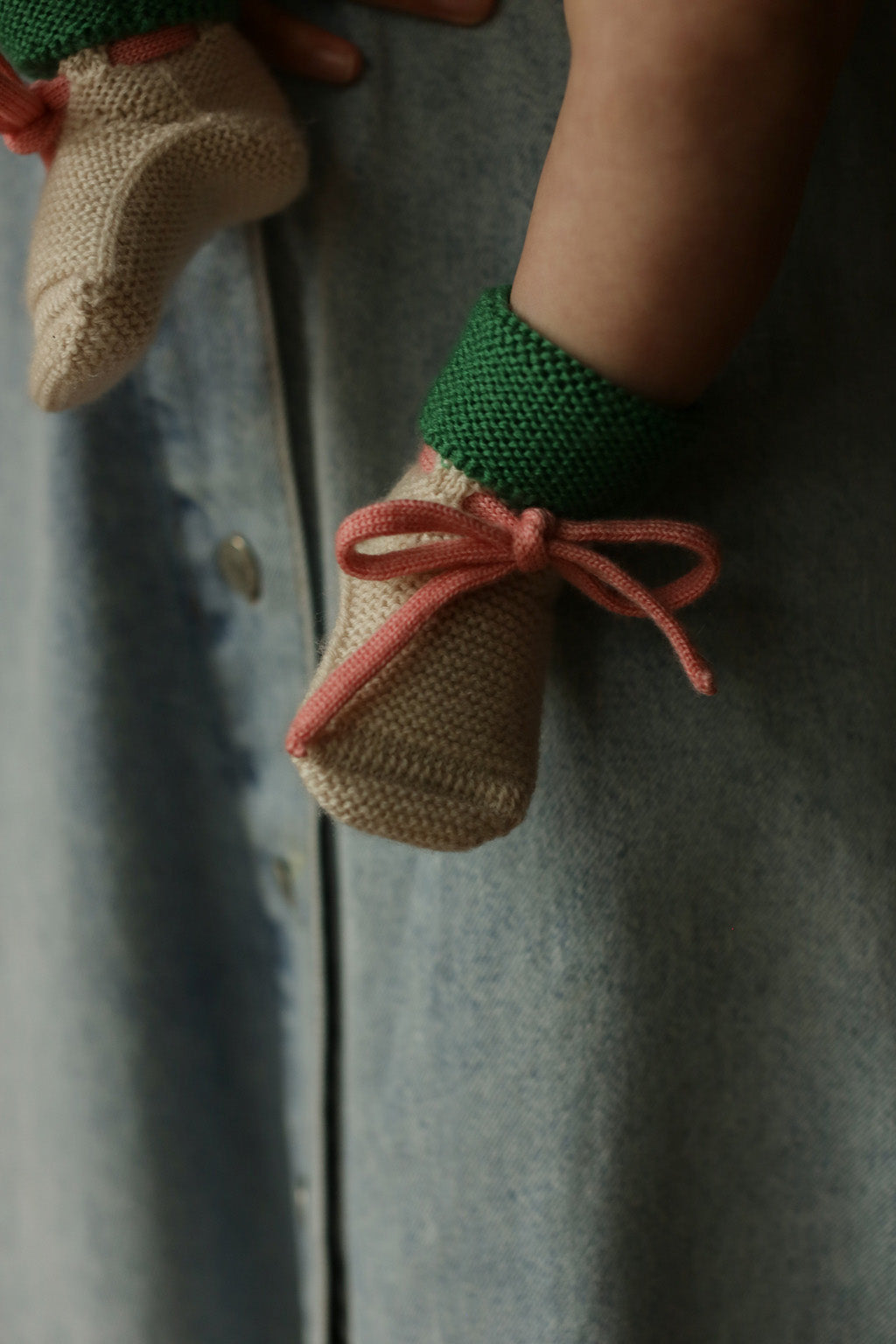 Baby trägt die Hvid Strickschuhe Booties in Cream/Grass, erhältlich bei Bärechind