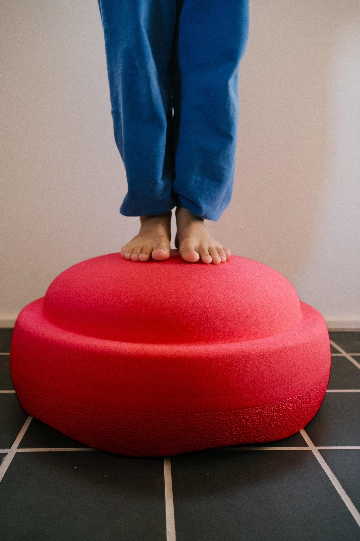 Kind steht auf einem roten Schaumstoff-Balanceelement und trainiert Gleichgewicht.