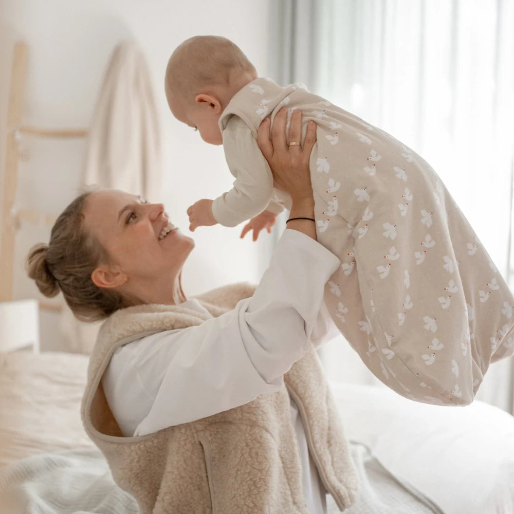 Emma & Noah Kugelschlafsack mit 2.5 TOG in Beige beim Anziehen eines Babys, erhältlich im Bärechind in Winterthur, Zürich, Schweiz.