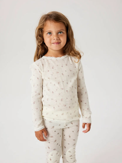 Kind trägt cremefarbenes Langarmshirt aus Wolle mit Blumenmuster – zu kaufen bei Bärechind in Winterthur, Zürich, Schweiz.