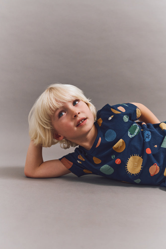 Kind trägt das LIEWOOD Apia T-Shirt mit Weltall-Print – kurzärmeliges Bio-Baumwollshirt mit Planeten-Motiv, erhältlich bei Bärechind Winterthur.