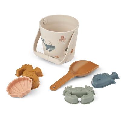 Liewood Gilma Strandeimer-Set in Sea Creature Sandy. Enthält einen Eimer mit Meeresmotiven, eine Schaufel und vier Sandformen aus weichem Silikon. Perfekt für kreativen Spielspass am Strand oder im Sandkasten. Erhältlich in Winterthur, Zürich, Schweiz.