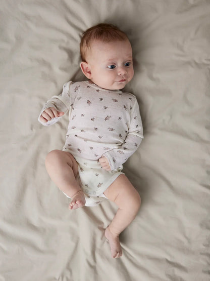Ein Baby trägt den Lil’Atelier Merino-Body mit Blumenmuster in Winterthur.

