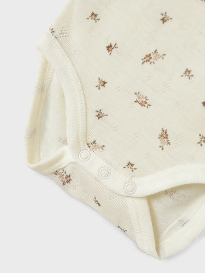 Detailaufnahme vom Knopfbereich des Lil’Atelier Merino-Bodys mit zartem Blumenmuster, erhältlich in Winterthur.