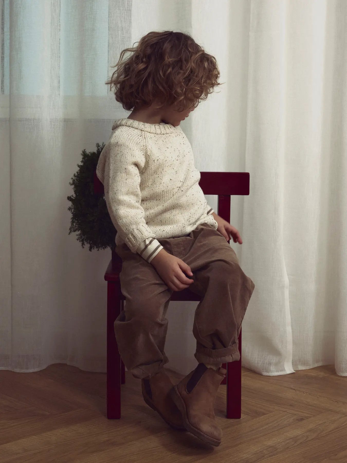 Kind trägt beigen LIL'ATELIER Strickpullover aus Bio-Baumwolle – erhältlich bei Bärechind in Winterthur, Zürich, Schweiz.