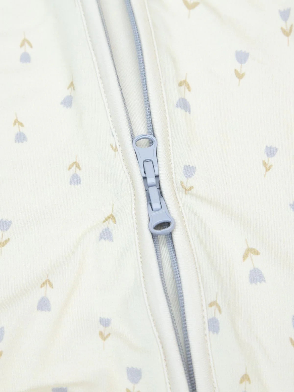 Detailaufnahme des LiluLila Bambus Zippy Stramplers mit praktischer Zwei-Wege-Reissverschluss-Funktion und nachhaltigem Tulpenprint.