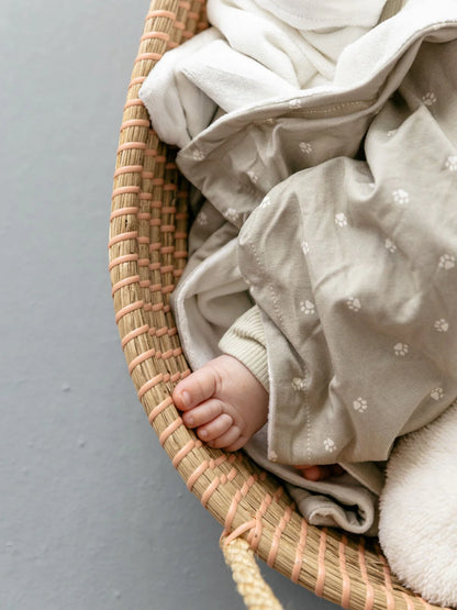 Baby liegt eingewickelt in die weiche LiluLila Löwen Pfötchen Bambus Baby Decke. Nachhaltig, hypoallergen und atmungsaktiv – perfekt für sanfte Träume.