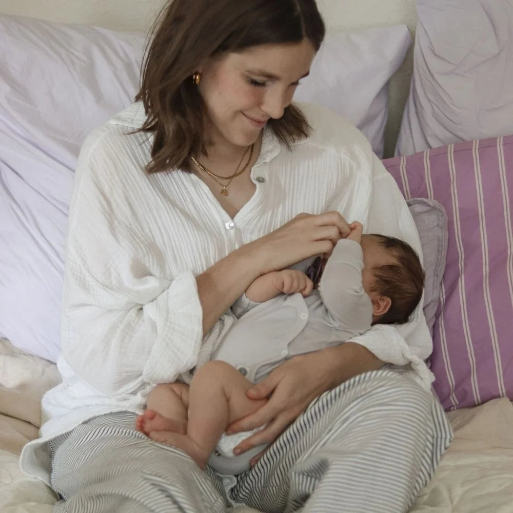 Baby im grauen Emma & Noah Merino Wickelbody auf dem Arm seiner Mutter, erhältlich im Bärechind in Winterthur und online in der Schweiz.
