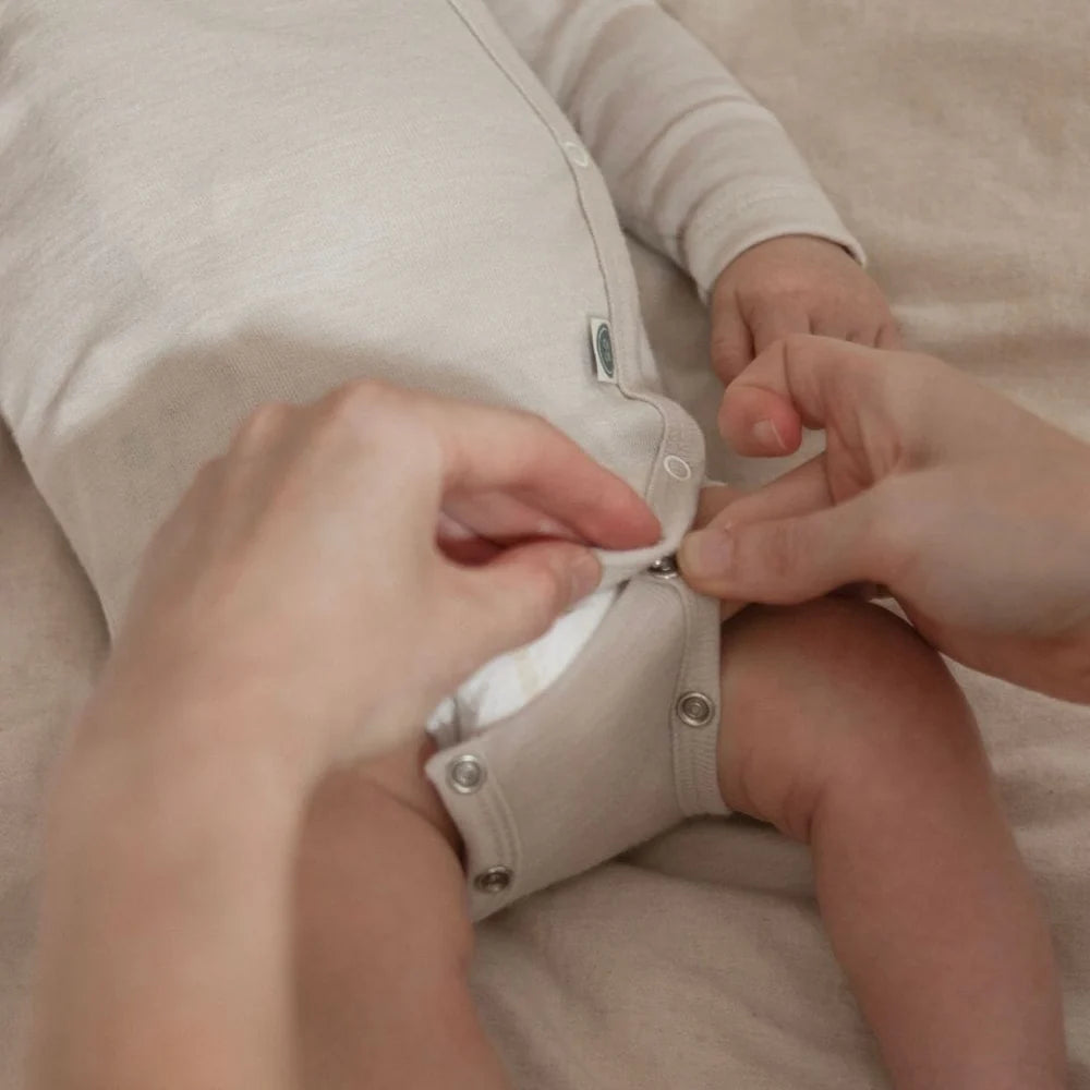 Detail der Druckknöpfe am beigen Emma & Noah Merino Wickelbody für einfaches Wickeln, erhältlich im Bärechind