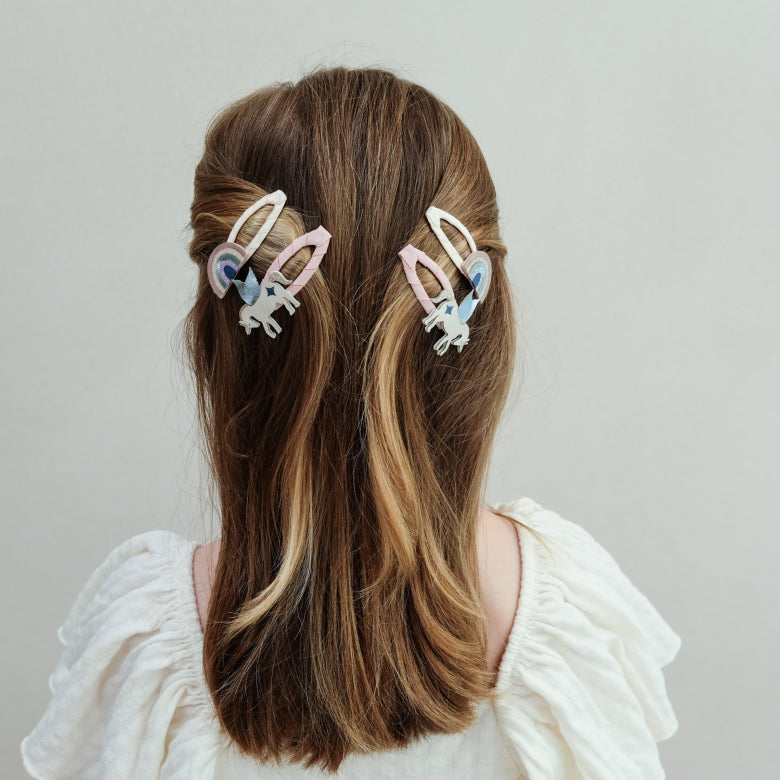 Mädchen trägt Mimi & Lula Haarclips mit Einhorn und Regenbogen im Haar.