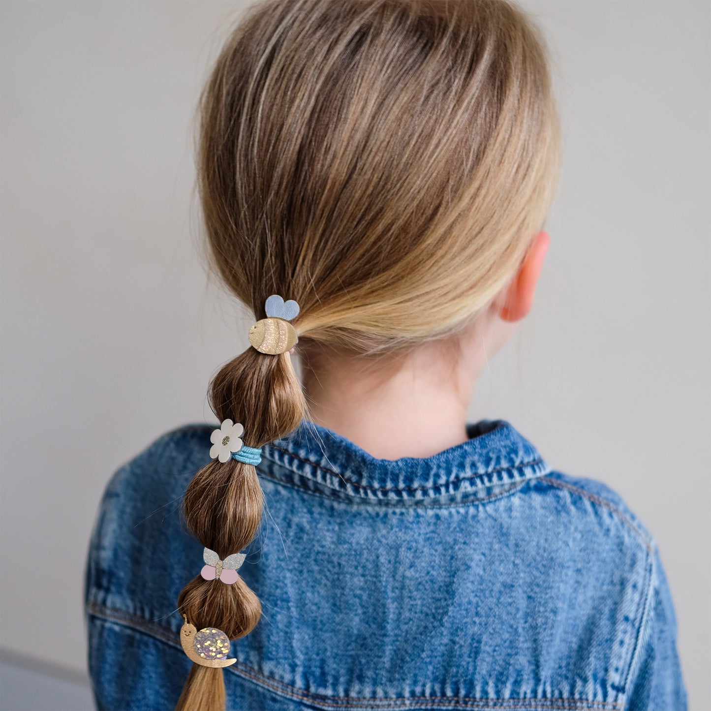 Kind trägt Mimi&Lula Haargummis mit Biene, Schnecke und Blume im Zopf, erhältlich bei Bärechind in Winterthur, Zürich, Schweiz.