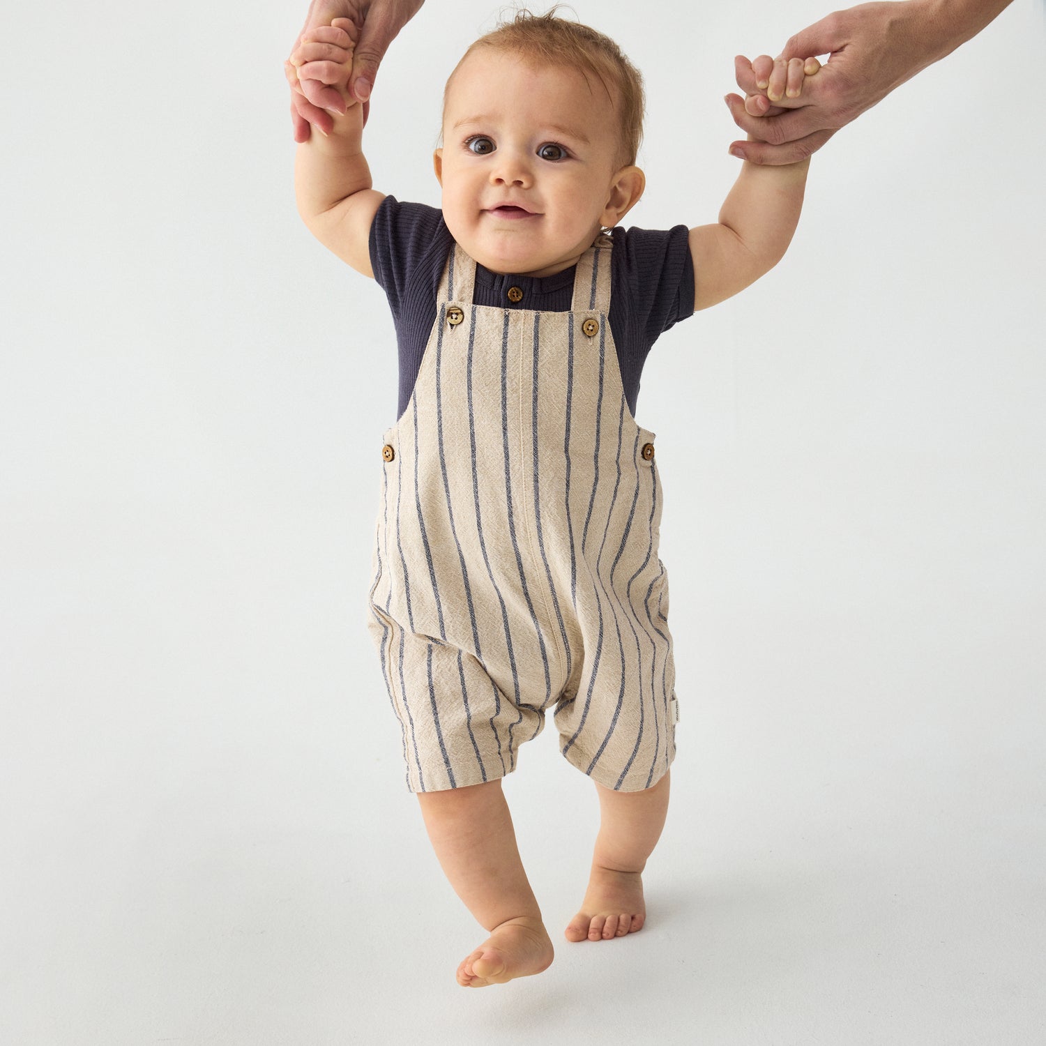 Baby trägt Minymo Latzhose aus Baumwolle mit Streifen – nachhaltige Baby- und Kindermode im Bärechind Winterthur, Zürich Schweiz.