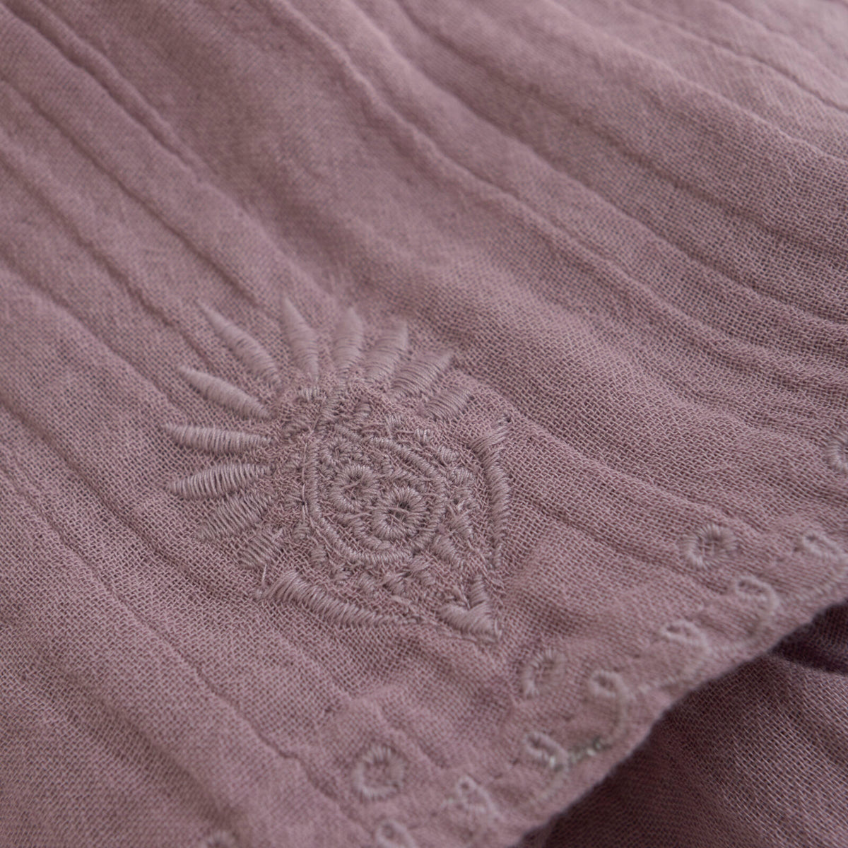 Detailaufnahme des Minymo Musselinrocks in Lila mit feiner Blumenstickerei und weicher Stoffstruktur.