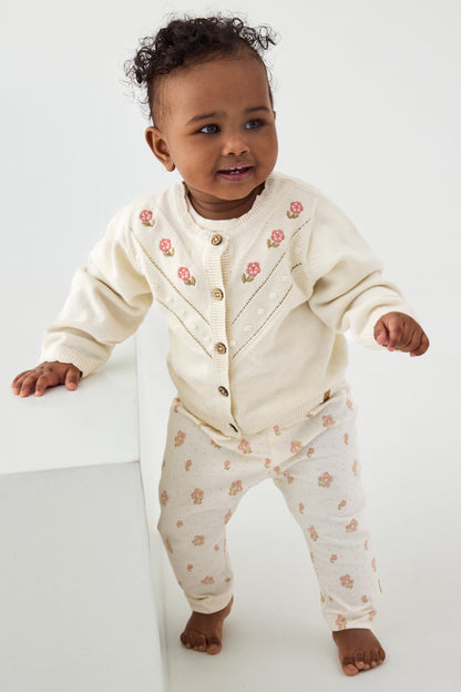 Baby trägt weisse Minymo Strickjacke aus Bio-Baumwolle im Bärechind Winterthur, Zürich, Schweiz