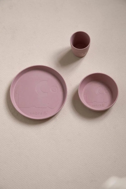 Rosa Teller, Schale und Becher des MUMS-Sets als Flatlay auf einem hellen Untergrund arrangiert.