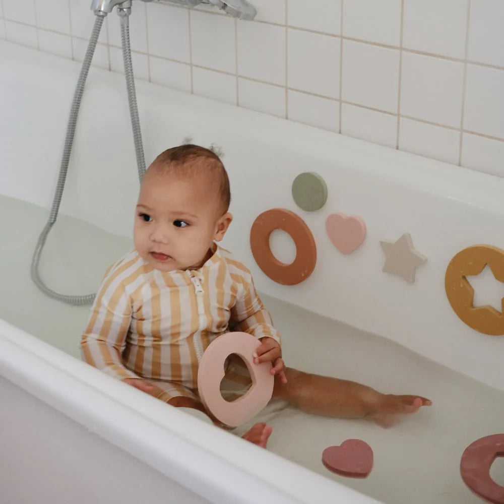 Mushie Schaumstoff-Badepuzzle mit bunten geometrischen Formen an der Badewannenwand, spielerisches Lernen beim Baden.
