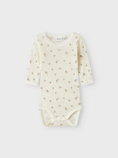 Ein Babybody aus Merinowolle von Name it  mit Blumenmuster, erhältlich in Winterthur.