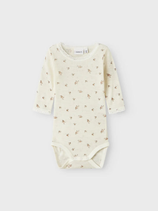 Ein Babybody aus Merinowolle von Name it  mit Blumenmuster, erhältlich in Winterthur.