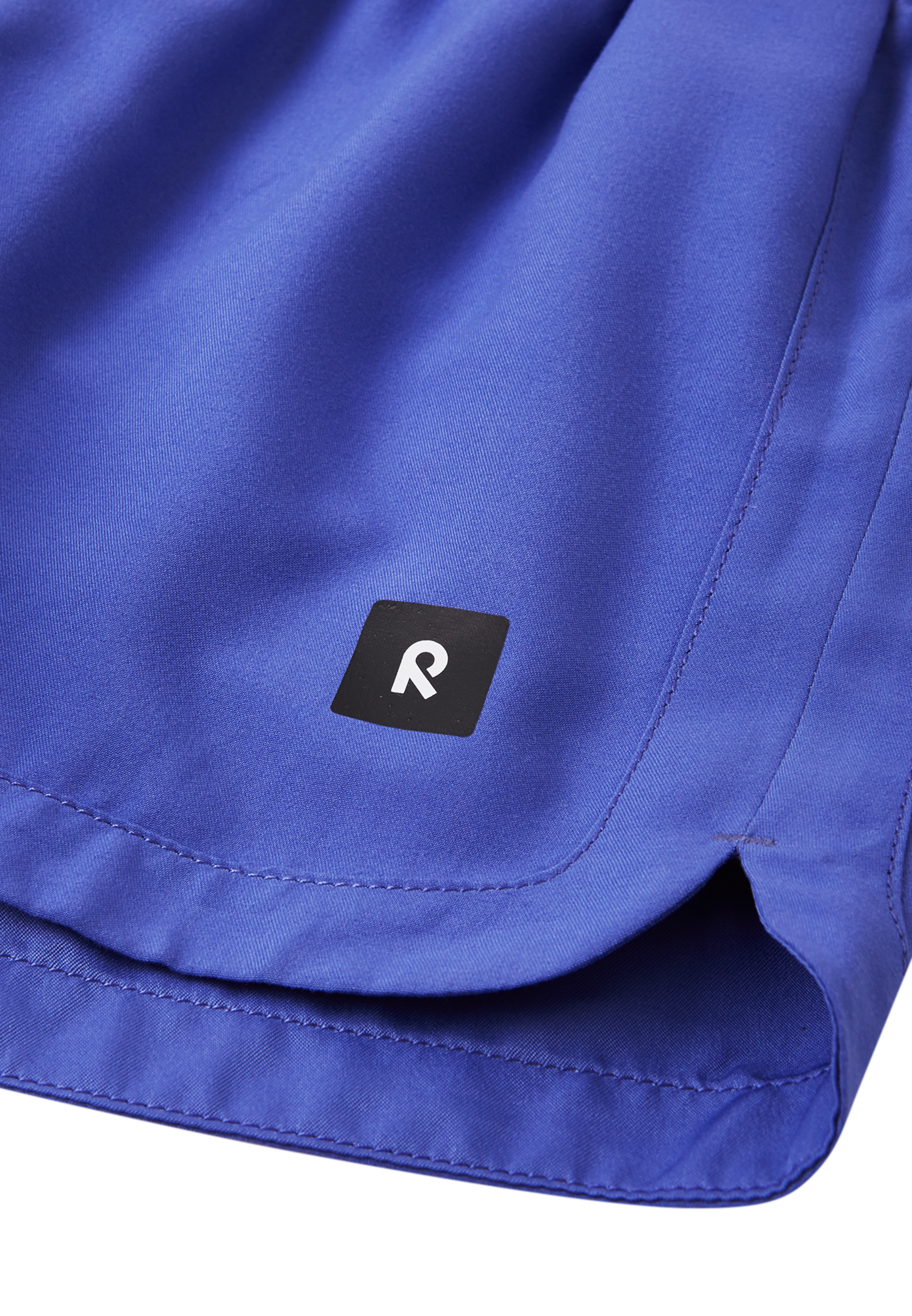 Detailaufnahme Logo & Saum der Reima Nauru Badeshorts – in Lila mit UV-Schutz
