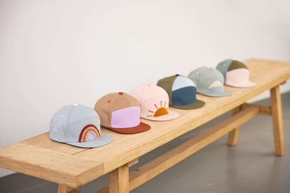 Lässig Skater Cap „Rainbow blue“ auf Holzbank – moderner Kinderstyle im Alltag